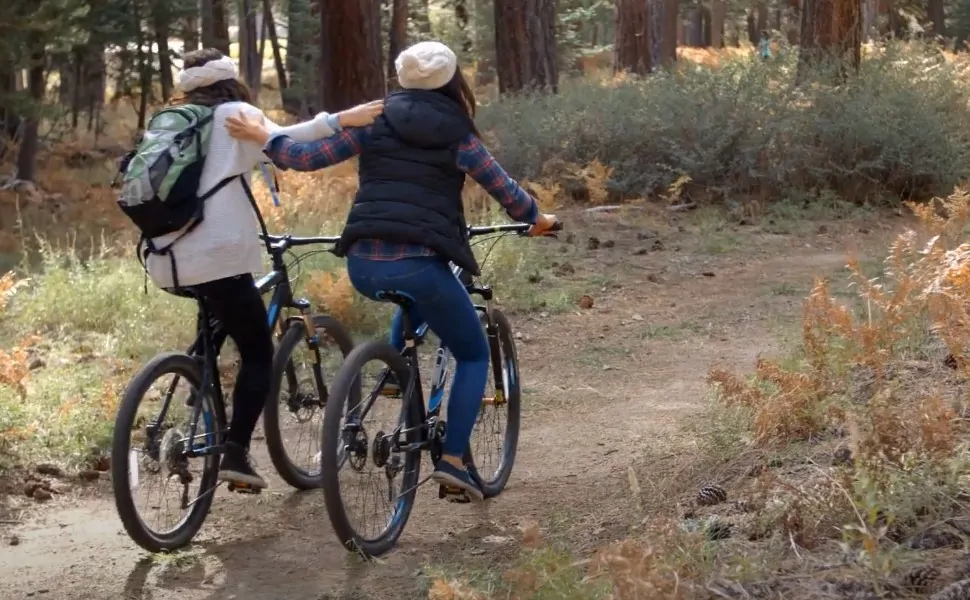 Two girls riding bikes through the forest