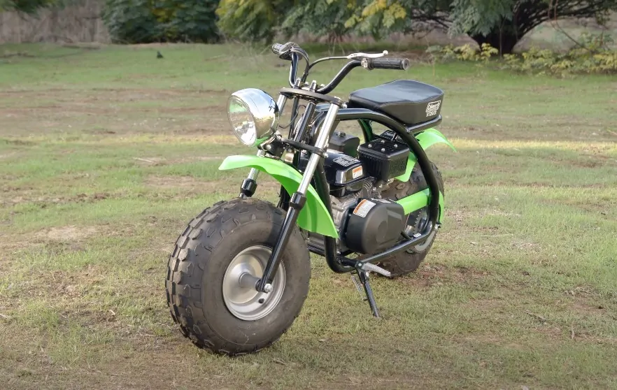 Green Coleman mini bike parked on the grass