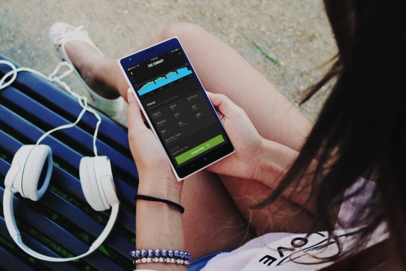 A girl check TrainerRoad app while sitting on a park bench