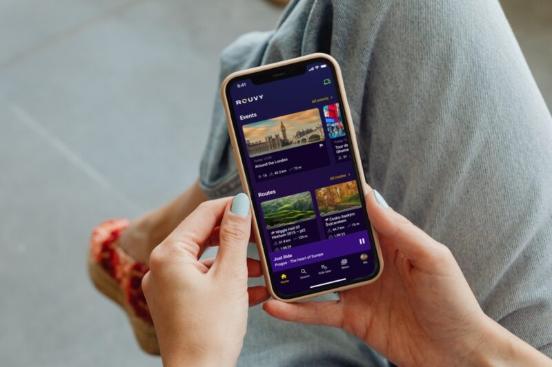 A girl holding a phone with Rouvy bike app on it