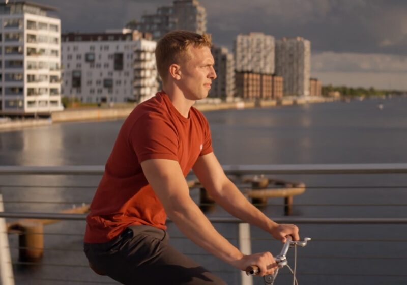 A guy is cycling in a city over a bridge