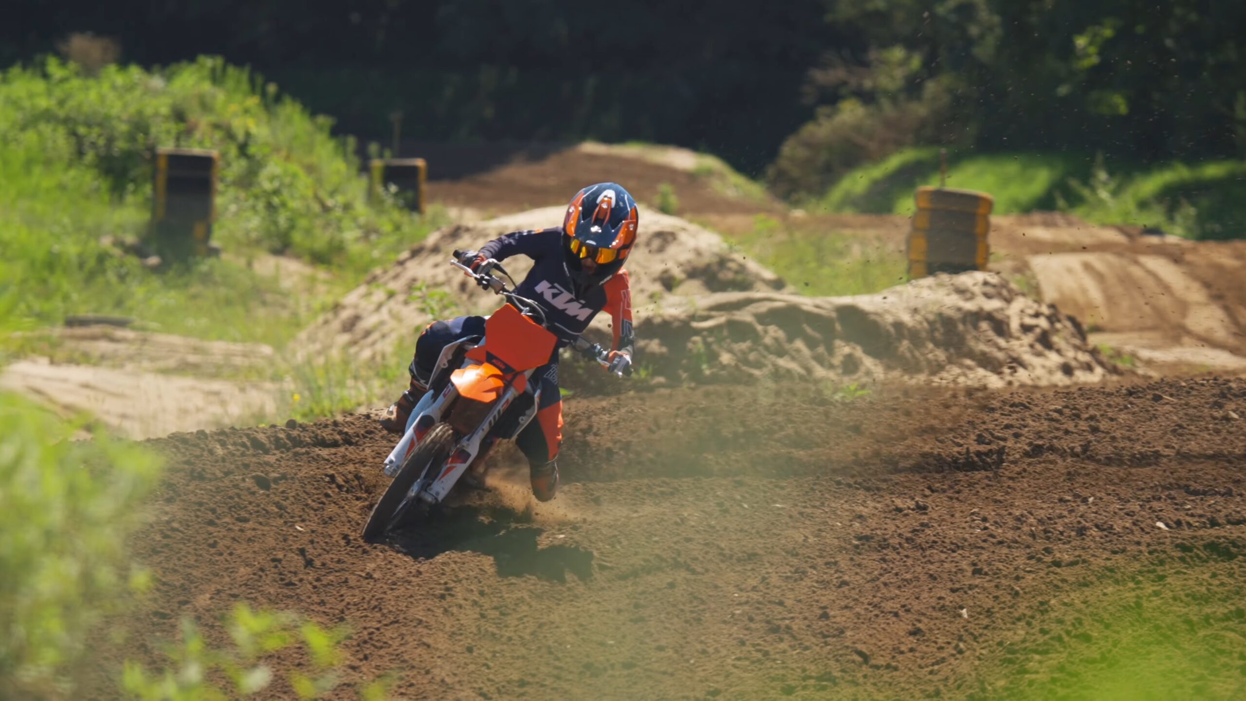 Kid with helmet riding small orange dirt bike