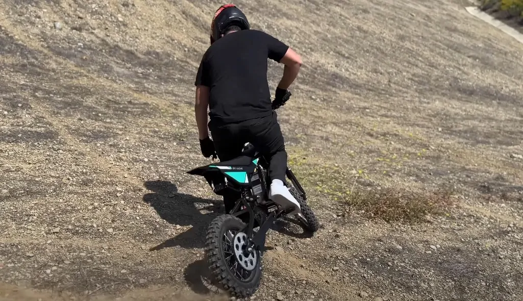 Guy with black helmet rides small dirt bike