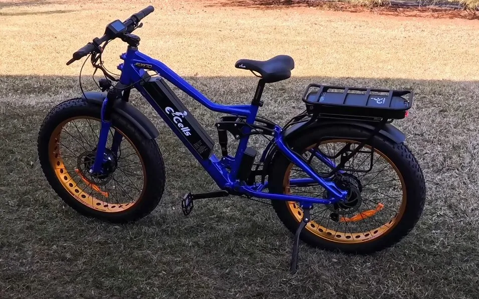 Blue e-bike standing on the beach with lake behind it