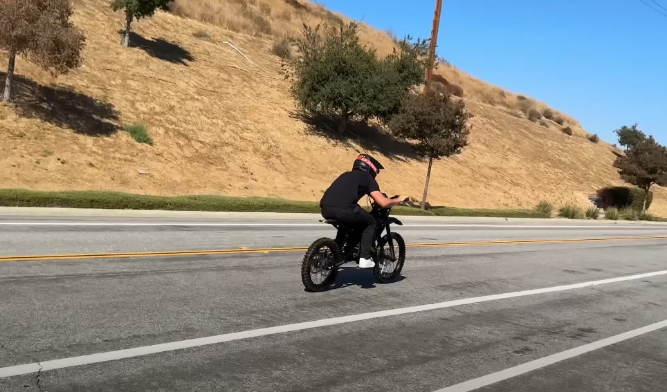 Guy with a helmet rides electric dirt bike on the road