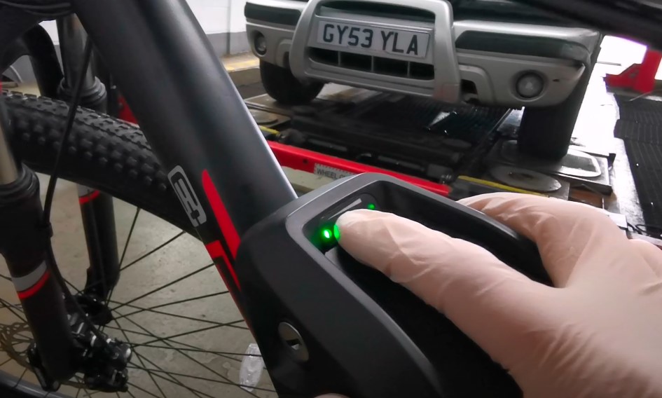 A guy's hand wearing gloves and pushing reset button on e bike