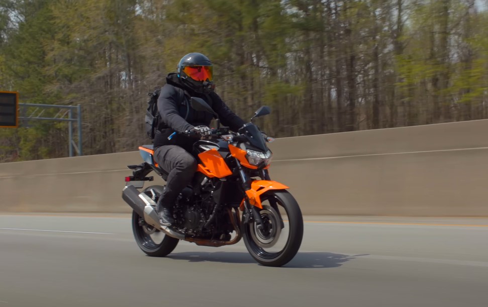 Biker dressed in black wears helmet on a red bike