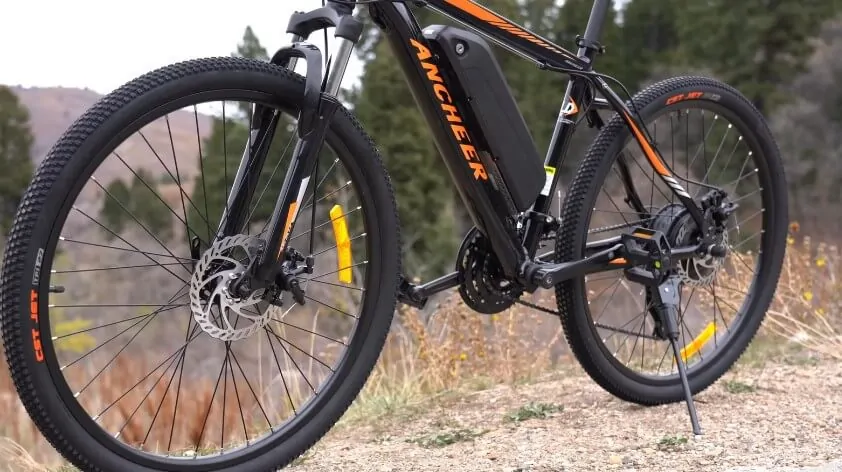 A robust, black electric mountain bike with bright orange accents