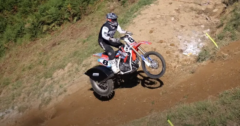 A motocross bike leaps over a dirt obstacle