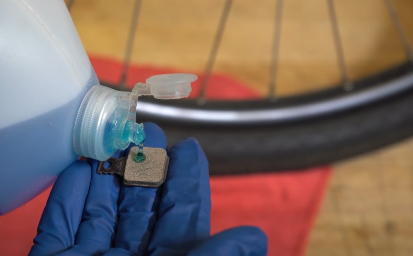 Applying a cleaning solution to bicycle brake pads for maintenance.