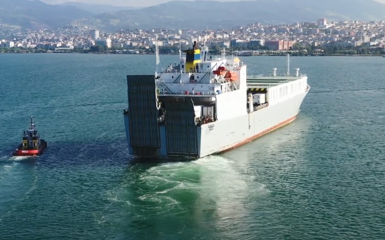 A large ship sails in the water alongside a small boat