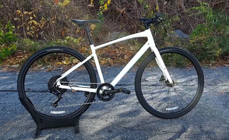 A white Specialized Sirrus 2.0 bicycle is parked on a black stand