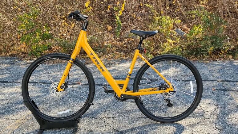 A yellow Trek Verve+ 2bicycle is parked on the side of the road