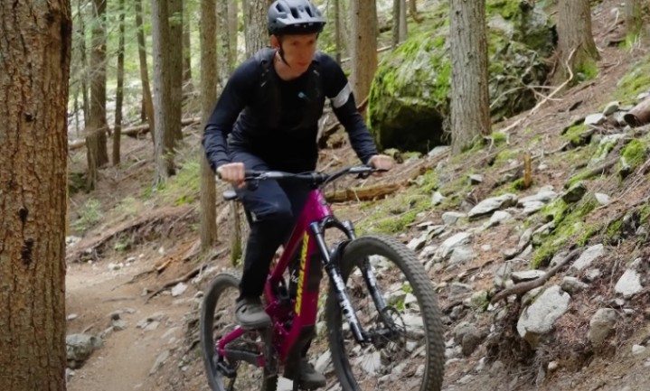 Kid riding a mountain bike through a forest trail