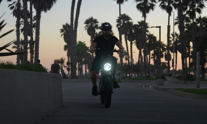 Man rides an e-bike after sunset, wearing helmet