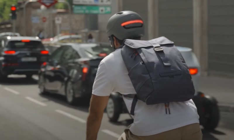 Man in white shirt, wearing smart helmet, riding e-bike
