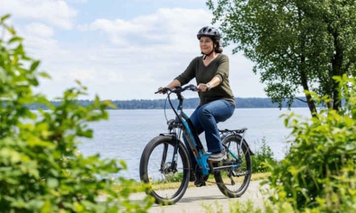Woman with helmet rides e-bike next to a waterfront