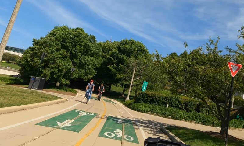 A person riding a bike along a scenic bike path surrounded by trees and greenery