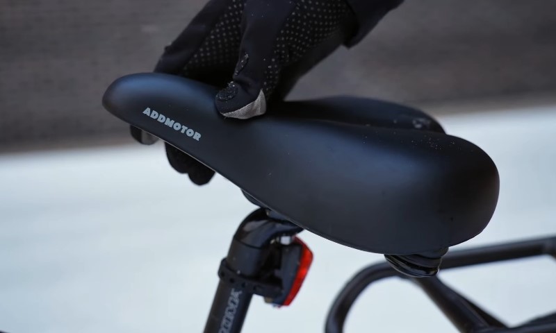 A person wearing gloves adjusts a black bicycle seat