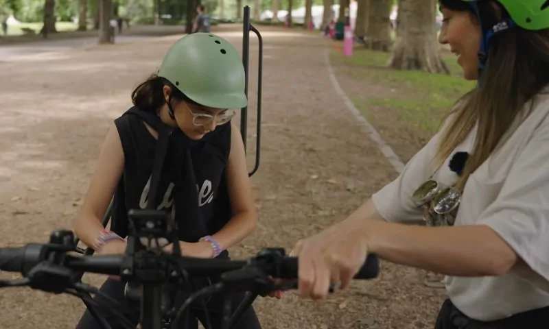 A woman assists a girl riding a bike