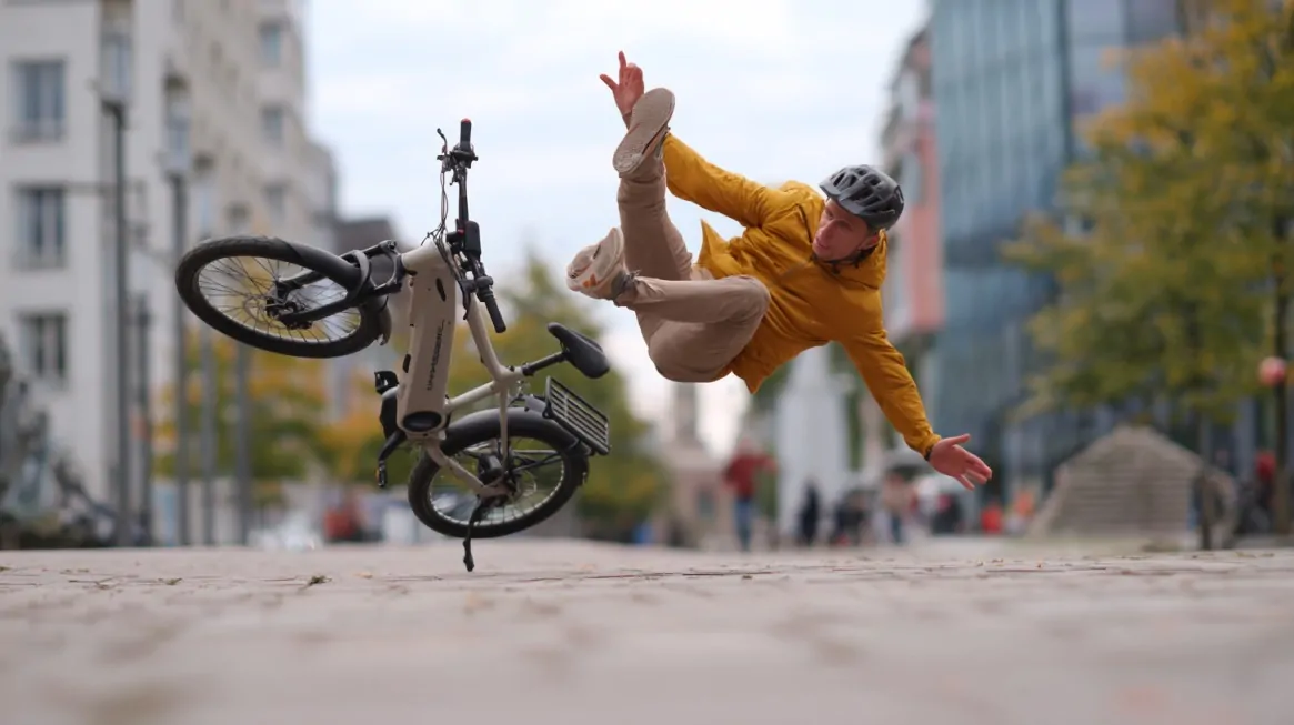 A cyclist falling off an electric bike on a city street while wearing a helmet