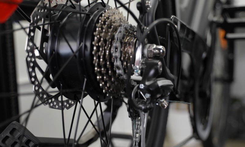 Close-up of a bicycle's rear wheel, highlighting the gear cassette, derailleur, and disc brake