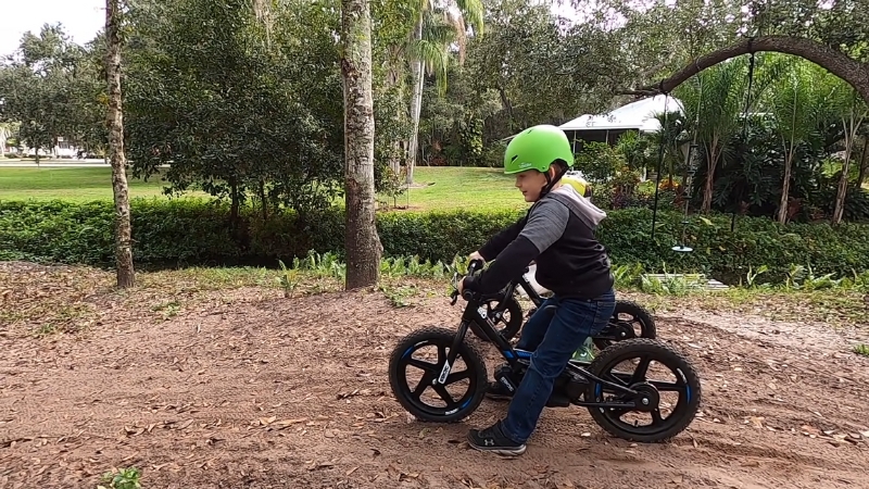 Child riding one of the top electric bikes for kids on a dirt path with a helmet