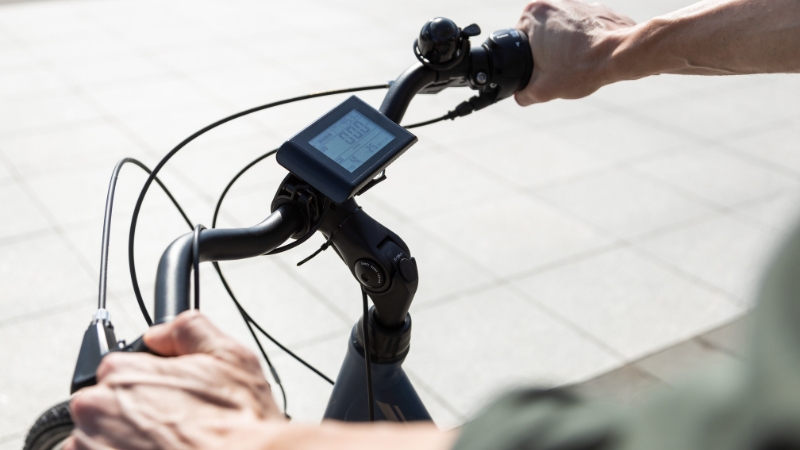 Close-up of a rider’s hands on an e-bike handlebar with a digital display screen