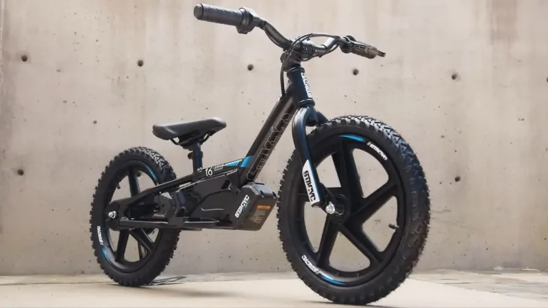 STACYC 16eDRIVE brushless electric balance bike with 16-inch wheels parked against a concrete wall