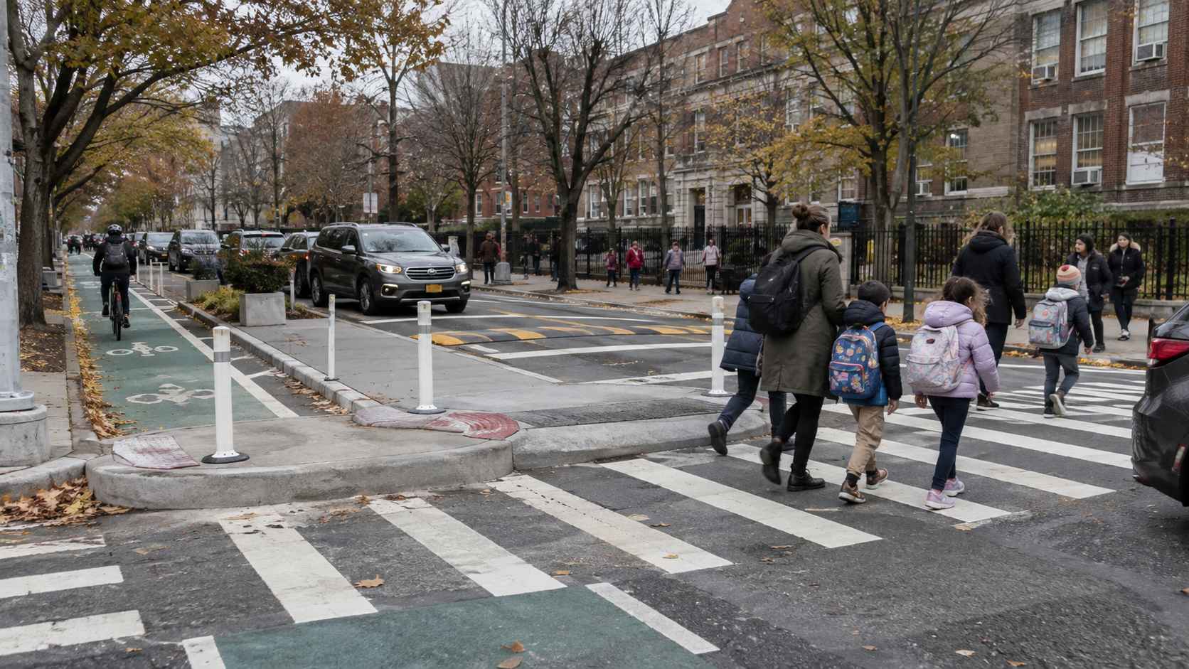 Parents and children cross a street beside a protected bike lane outside a New York City school.